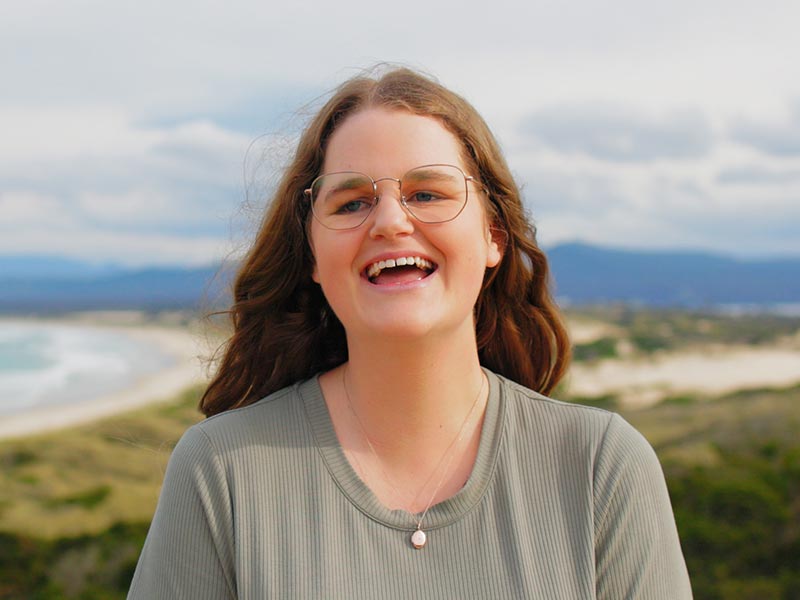 Young person impacted by cancer standing in front of the ocean. Donate through regular giving to cancer charity Canteen Australia