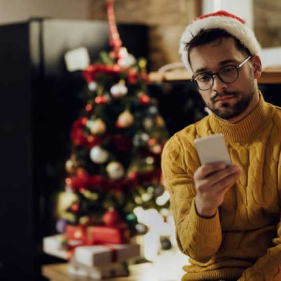 young person wearing a santa hat and looking at their phone