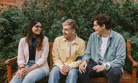 Three people sitting in the park talking