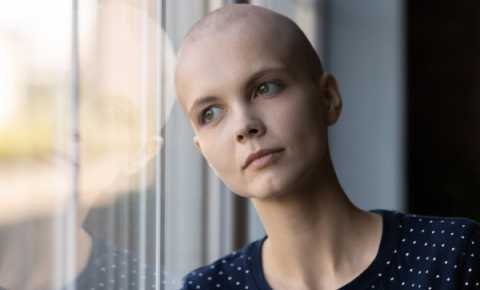 young person impacted by cancer leaning on a window