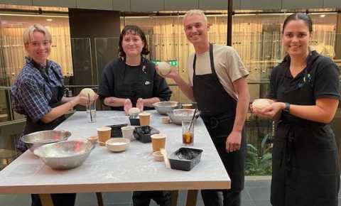 four young people making pizza