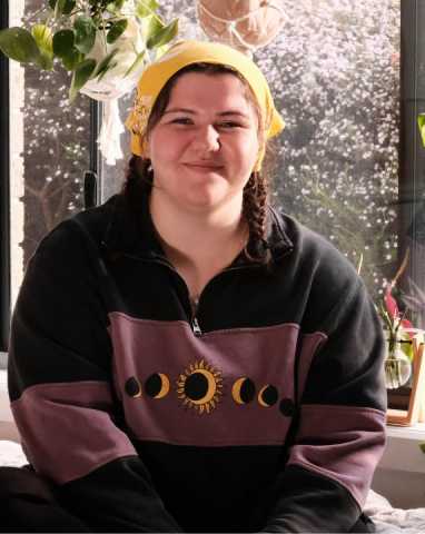 Tara, a young person impacted by cancer, smiling into the camera wearing a Canteen bandanna