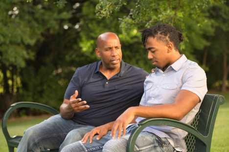 Father and son discussing cancer in a park