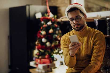 young person wearing a santa hat and looking at their phone