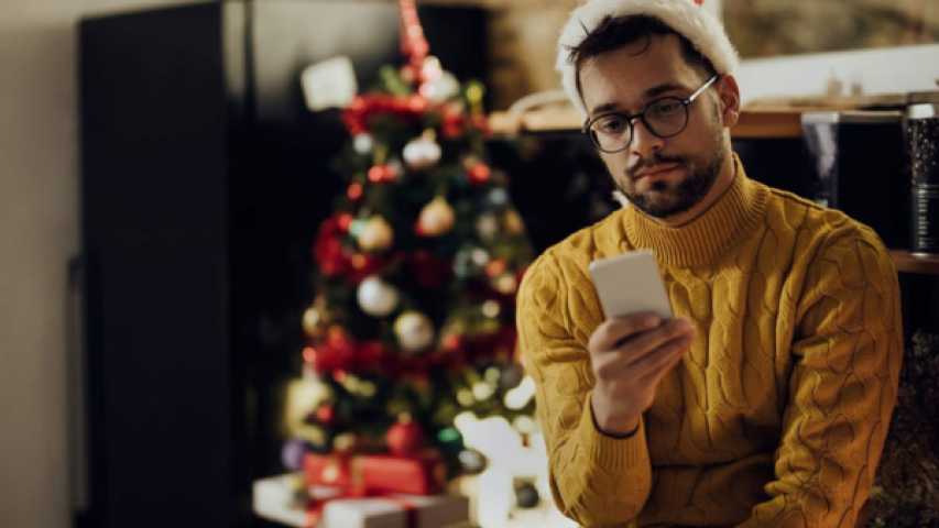 young person wearing a santa hat and looking at their phone