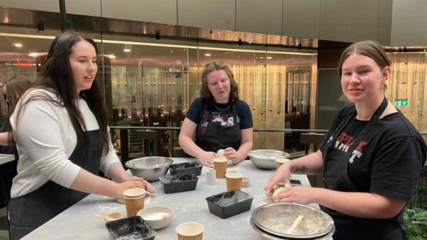 three young people making pizza